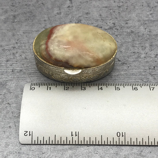 Silberfarbene Pillendose mit Verzierungen und mit Stein